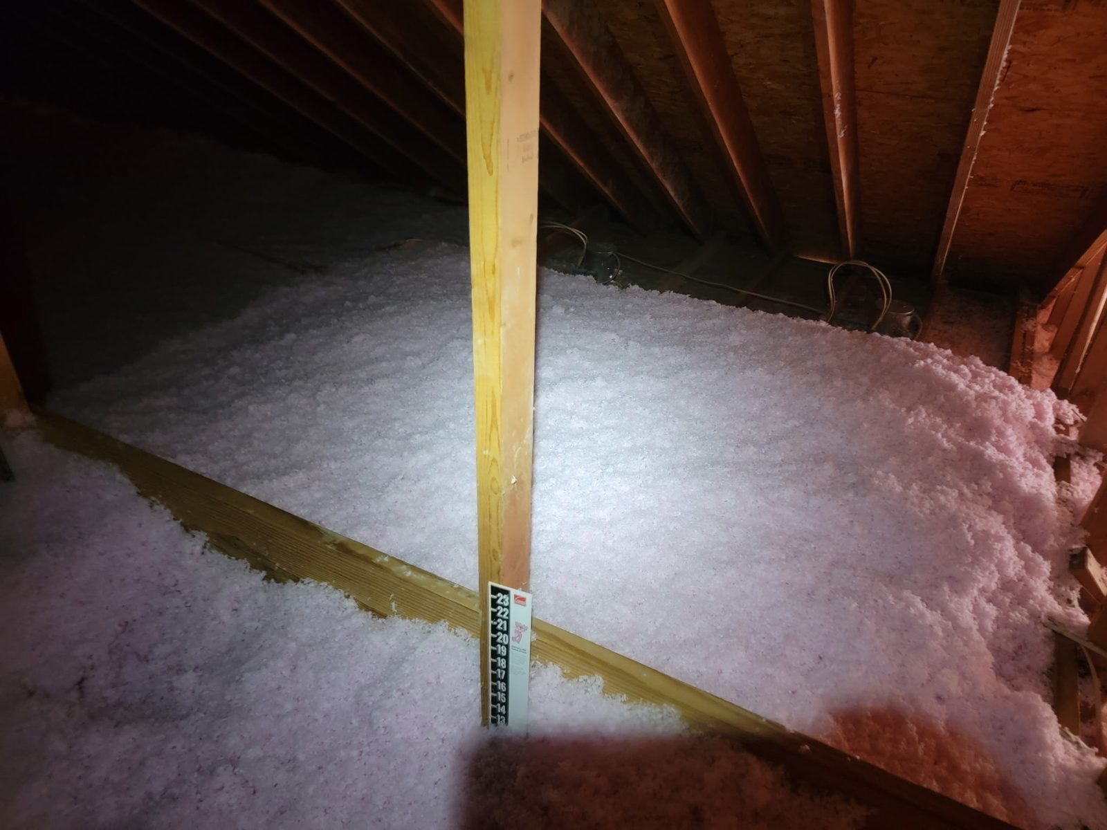 Attic insulation blown past 20 inches with depth gauge visible